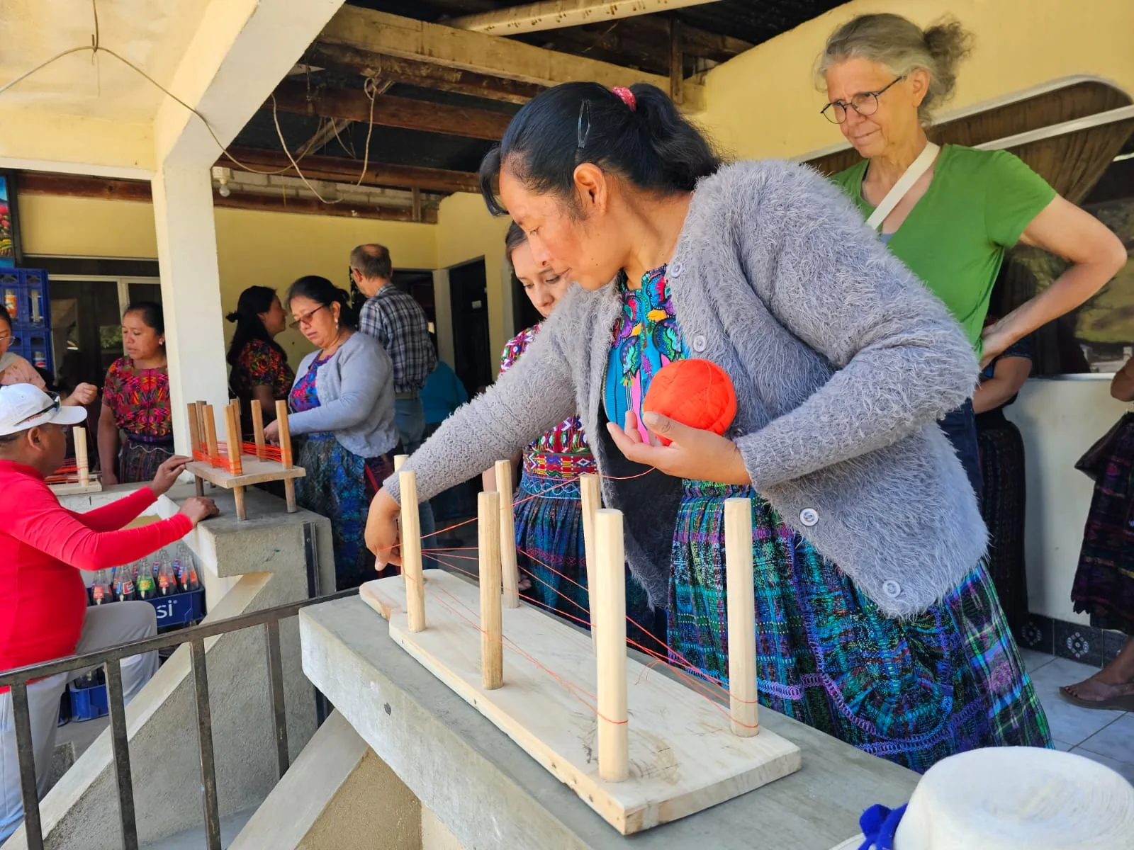 Maestra de tejido mostrando el proceso de urdimbre durante un taller